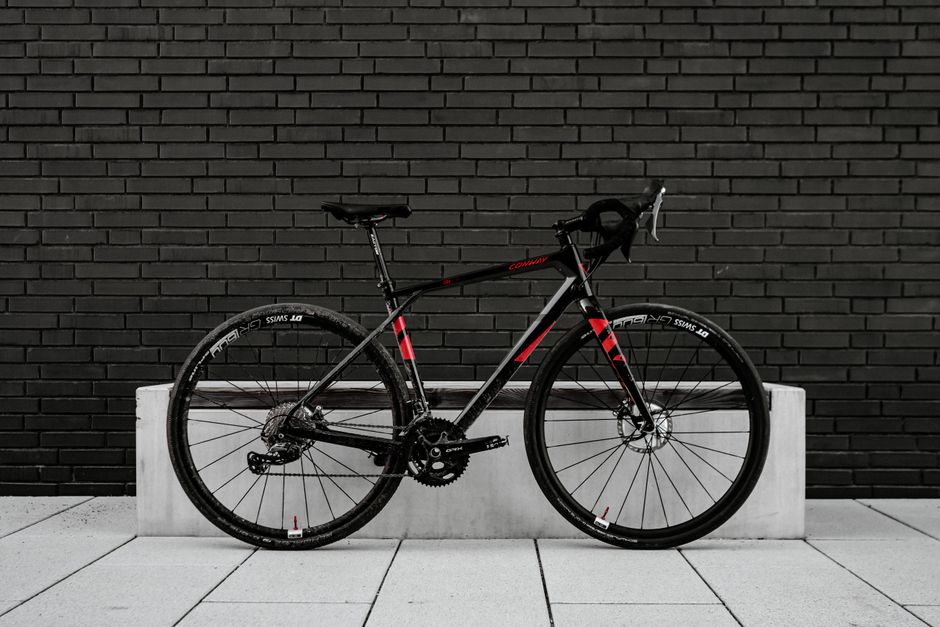 Sleek black and red road bike leaning on a modern brick wall.